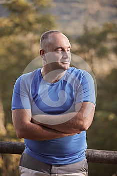 One young overweight man, 30-35 years, looking sideways, arms crossed, outdoors portrait, upper body shot