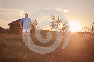 One young overweight man, 30-35 years, proud, posing standing, golden orange sunset,
