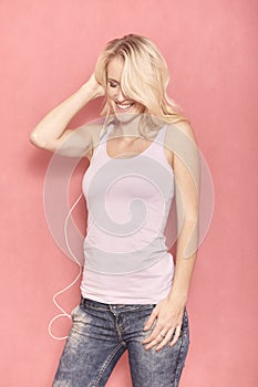 One young smiling woman, eyes closed, beautiful candid smile and bright teeth, while listening to music on her earbuds