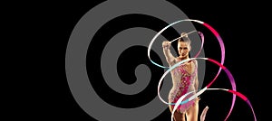 One young sportive girl, rhythmic gymnastics artist performing with ribbon isolated on dark background. Concept of sport