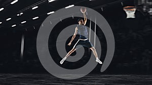 One young sportsman basketball player training in gym, idoors isolated on dark background. Concept of sport, game