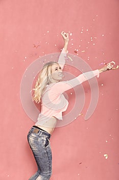 One young woman happy with arms outstreched high in air with confetti thrown