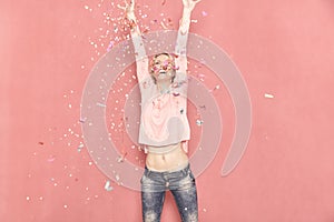 One young woman happy with arms outstreched high in air with confetti thrown, 20-29 years old, long blond hair.