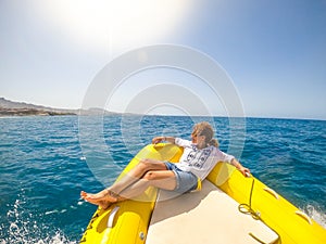 One young woman lying on a boat traveling and discovering the sea enjoying and relaxing with a sunny day - looking at the coast