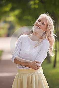 One young woman portrait, 25 years old, yellow dress, white top, park, smiling happy