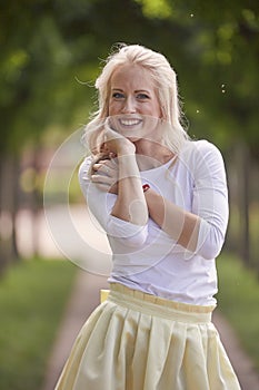 One young woman portrait, 25 years old, yellow dress, white top, park, smiling happy