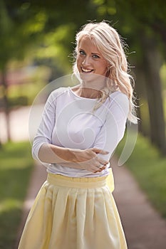 One young woman portrait, 25 years old, yellow dress, white top, park, smiling happy