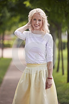 One young woman portrait, 25 years old, yellow dress, white top, park, smiling happy