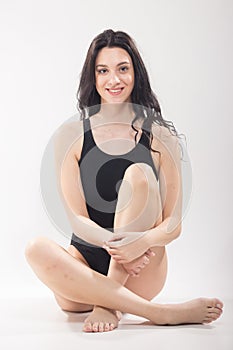 One young woman, sitting swimsuit, legs crossed