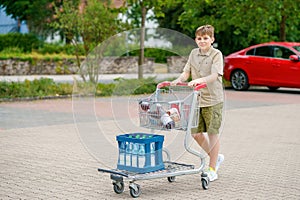 onfident School Boy Pushes the Shopping Cart Through a Bustling Supermarket. Handsome Teenager Gathers Groceries and