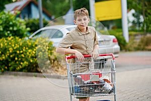 onfident School Boy Pushes the Shopping Cart Through a Bustling Supermarket. Handsome Teenager Gathers Groceries and