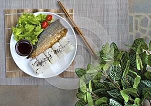 Onigiri and grilled fish with sauce put on white plate decorted
