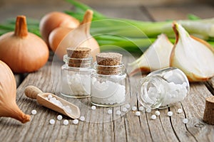 Onion bulbs, green onions and bottles of homeopathic globules. Homeopathic remedies