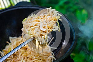 Onion cut into half rings is fried in a cauldron in vegetable oil. The scoop stirs the fried onions. Fresh and wholesome food.