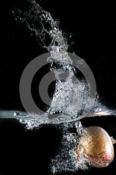 Onion disguised as a halloween monster, immersed in water, on a black background