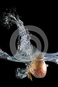 Onion disguised as a halloween monster, immersed in water, on a black background