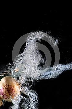 Onion disguised as a halloween monster, immersed in water, on a black background