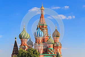 Onion domes of St. Basil`s Cathedral in Moscow against blue sky on a sunny summer evening