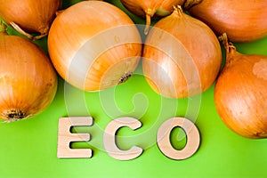 Onion Eco product or food. Onions bulb are on green background with text eco wooden letters. Example of sustainable environmentall