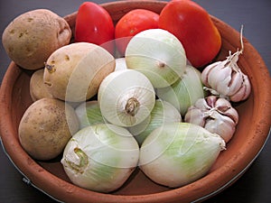 Onion Garlic Potato Tomato Vegetables. Closeup of fresh organic vegetables in a clay dish