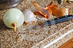 Onion husk peeled bulb and knife on marble table