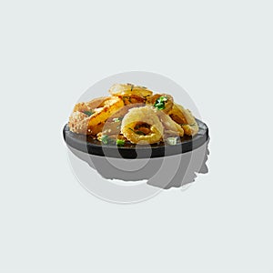 Onion rings in batter sprinkled with greens on wooden plate with shadow isolated on white.