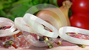 Onion rings falling on a meat beef steak on a wooden board.