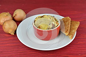 Onion soup gratinated with bread and cheese on red wood