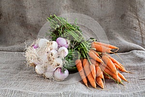 Onions and carrots on wooden background and sack