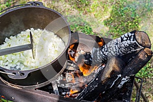 Onions are cooking in the pot on the fire for pilaf