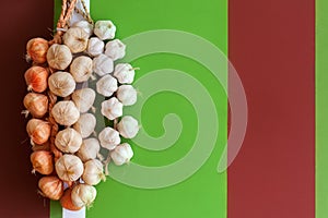 Onions and garlic in a bundle on bright multi-colored stone wall