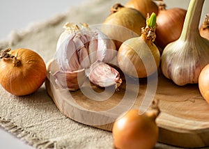 Onions and garlic lie on the table on a wooden board and a canvas napkin