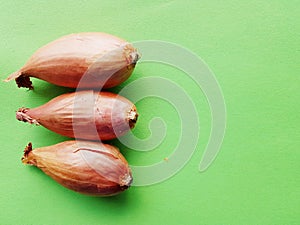 Onions over green table with copy space. Closeup of three onions.