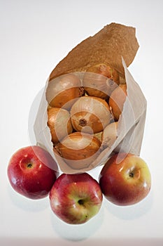 Onions in a paper bag and an apple, white background, fruit and freshness, aphorisms written on paper
