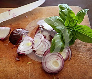 Onions slices and basil on the chopping board