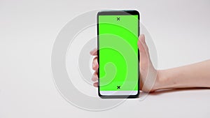 Online advertising. Close-up of female hand holding smartphone with green screen on white background. Man swipes at