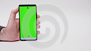 Online advertising. Close-up of man's hand holding smartphone with green screen on white background. Concept of apps