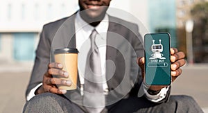 Cropped of black man in suit holding smartphone, using chatbot