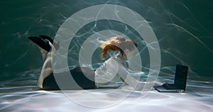 Online assistant concept. Young beautiful business woman dives under water to use laptop, consult customers slow motion.