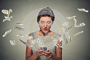 Online banking concept. Shocked woman using smartphone dollar bills flying away