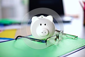 Online banking and investment concept with a pink ceramic piggy bank standing over a white and aluminium computer