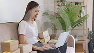 Online business concept, Asian business woman checking online orders on laptop to prepare delivery