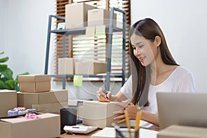 Online business concept, Asian business women writing address customer on parcel boxes for delivery