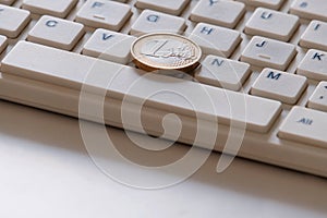 Online business. The concept of on-line sales. Coin in one Euro on the computer keyboard close-up. Spacebar and latin letters. photo