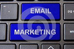 Online business and email marketing concept - Laptop keyboard with blue Email Marketing button.