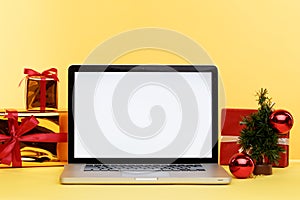 Online christmas shopping concept on the laptop display. White screen on the computer and gifts with paper bags near.