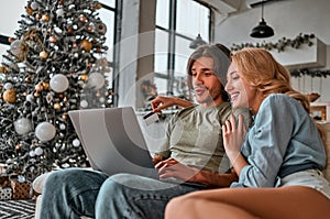 Online Christmas shopping. Happy smiling couple using credit card to internet shop. Young couple with laptop and credit card