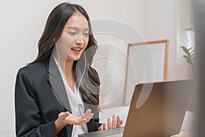 Online communication, attractive asian young woman in formal suit, using laptop computer having online virtual job interview