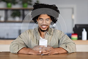 Online Communication. Black Guy Using Smartphone While Sitting At Table In Cafe