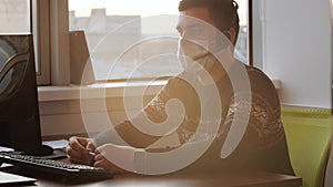 Online computer training during the coronavirus pandemic. Man in a medical mask performs work at a computer.